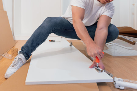 Professional carpenter assembling furniture on parquet floor of a new apartmentの写真素材