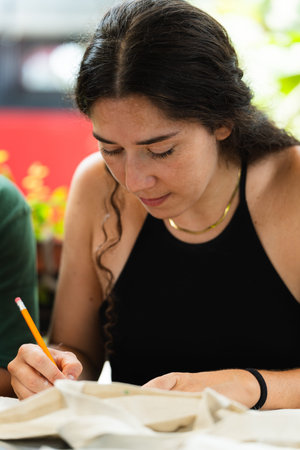 Young woman writing with a pencil during her return to university. Vertical