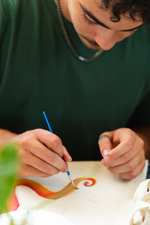 Young man painting with a brush in college fine arts class. Verticalの写真素材