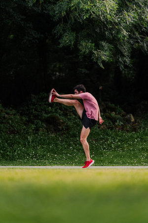 Young man lifting his legs to warm up before going for a run. Verticalの写真素材