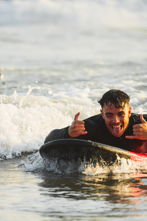 Brown-haired man enjoying surfing lessons for the first time