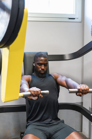 Black man working out hard on a gym machine