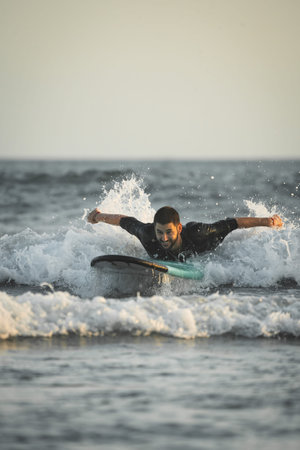 Surfer swimming hard on top of his surfboard to catch a wave