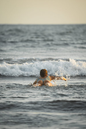 Female surfer swimming out to sea to start surfing