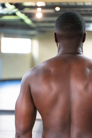 Shirtless back of a black bodybuilder in the gym