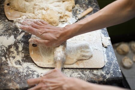 Top view of a piece of dough being rolled with a rolling pinの写真素材
