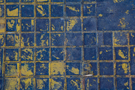The texture of a manhole cover drenched in yellow paint.の写真素材