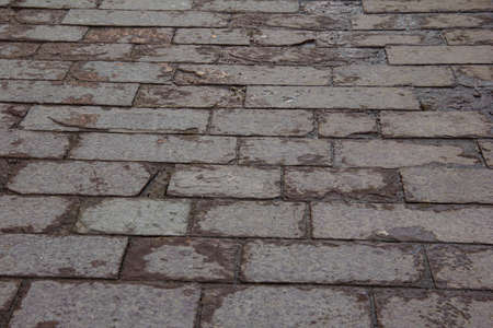 Cracked rectangular tiles on the sidewalk.の写真素材
