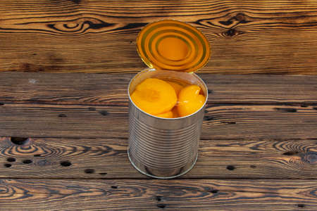 A can of canned peaches on a wooden table.の写真素材
