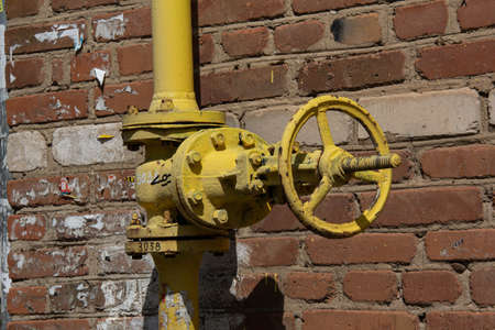 Yellow gas tap on the background of a brick wall.の写真素材