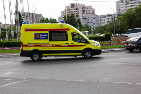 Orenburg, Orenburg region, Russia - 06.08.2021: An ambulance in the flow of vehicles with the beacons turned on. Inscriptions on the car: "Health of Russia", "emergency medical care".のeditorial素材