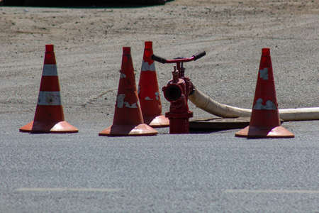 A fire hydrant on the roadway surrounded by orange cones.の写真素材