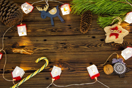 Christmas tree toys and sweets on a wooden background among pine branches.
