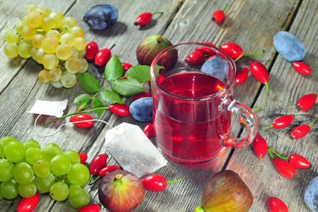 Dog rose tea and autumn fruits on a wooden tabeの写真素材