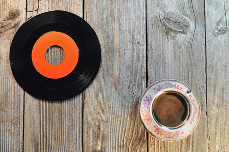 Old vinyl record and cup of coffee on a wooden tableの写真素材
