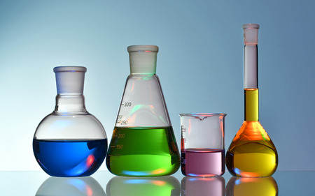 Laboratory glassware with colorful liquids and chemicals on blue background