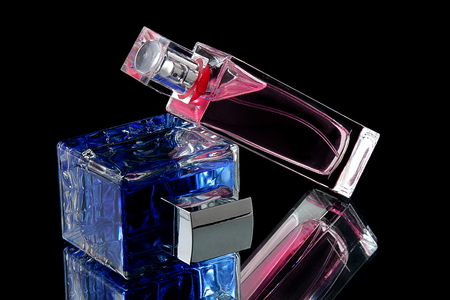 blue and pink perfume bottle with reflection on black backgroundの写真素材