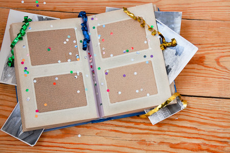 open old album with photo, tinsel and confitti on wood   