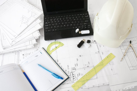 helmet, laptop and drawing tool on a plan.