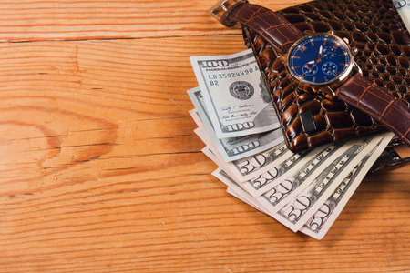 wallet with paper currency and wrist watch on wooden tableの写真素材