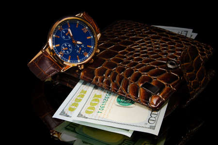 wallet with hundred dollar bill and watch on black backgroundの写真素材