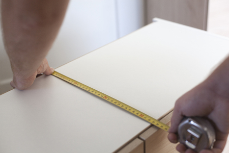 A man measuring a cupboard with a meterの写真素材