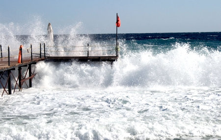 Red warning flags after a storm on a pier 