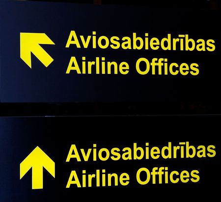 A black sign with little yellow round pictures to give and show direction at the airport indoorsの写真素材