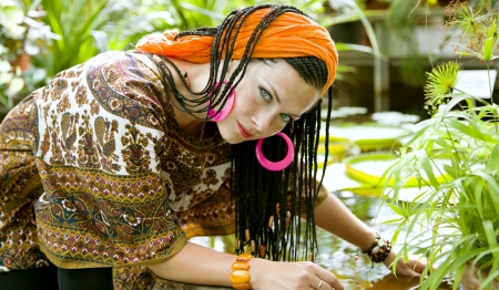  Beautiful blue-eyed woman with the african pigtails among tropical plantsの写真素材
