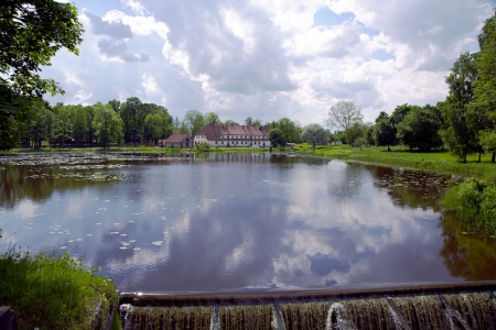 Beautiful lake with a little waterfall in the park of Jaunpils castle, Latviaの写真素材
