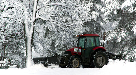 Snow cleaning tractor clears paths in a city park