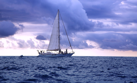 Yacht swimming in the Pacific ocean at sunset on a background thunderclouds.のeditorial素材