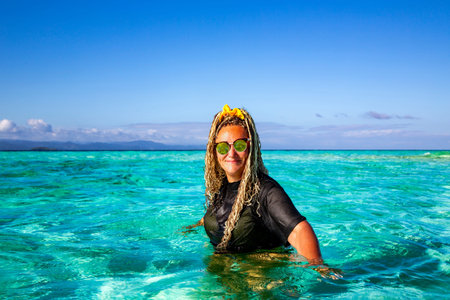Pretty woman in the crystal turquoise waters of the Indian Ocean on the Raja Ampat Islands,...