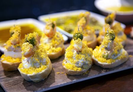 Appetizing spanish tapas with salad and grated egg yolk on a wooden tray in San Sebastian, Donostia, Spainの写真素材