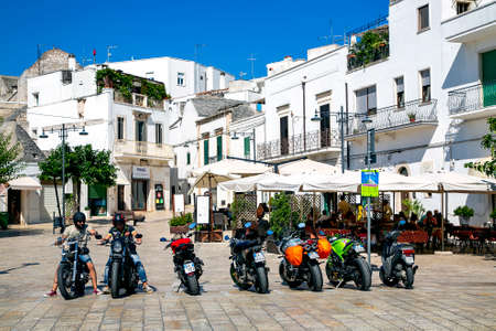 ITALY, BARI, AUGUST, 2017 - View of the sunny street of Bari with white houses and and parked scooters in front of the summer cafe in Bari, Puglia, Italyのeditorial素材