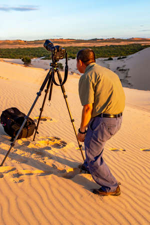 VIETNAM, MUI NE, NOVEMBER, 2016 - Photographer takes pictures with a tripod on the White Dunes, Vietnamのeditorial素材
