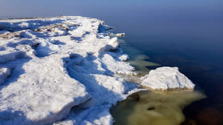 Unusually calm Baltic Sea with ice on the shore on a winter sunny day in Riga, Latviaの写真素材