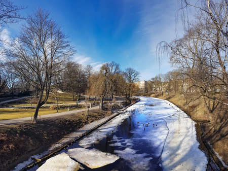 A winter view along a frozen Riga canal in sunny day. The canal flows through Bastion Hill park in Riga, Latvia.の写真素材