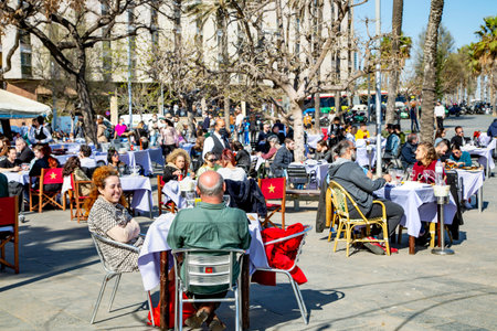 Spain, Barcelona, March, 2021: People dine on the open verandas of cafes and restaurants on the...