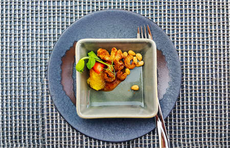 Fried small shrimps with pine nuts with light sauce on a gray plate a compliment from the restaurant chefの写真素材