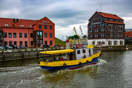 Lithuania, Klaipeda, July, 2020 - Yellow cargo barge sails along the canal in the Baltic Sea against...
