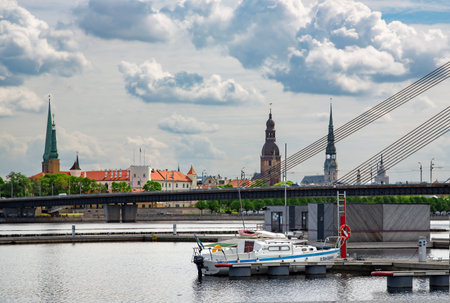 LATVIA, RIGA, JULY, 2021 - A pleasure yacht stands near a wooden pier on the Daugava river against...