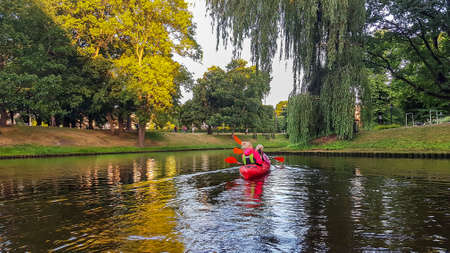 LATVIA, RIGA, JULY, 2021 - Active people enjoying paddling kayak on a Riga city canal, capital of Latvia. Tourists sailing on kayaks.のeditorial素材