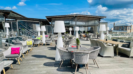 LATVIA, RIGA, AUGUST, 2021 - An open veranda of the restaurant with white wicker furniture and a...