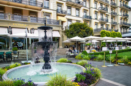 SWITZERLAND, INTERLAKEN, AUGUST 2021 - Open veranda of the restaurant in a beautiful garden with a fountain of the Victoria - Jungfrau Five star Grand Hotel and Spa in Interlaken, Switzerlandのeditorial素材
