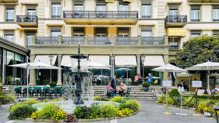 SWITZERLAND, INTERLAKEN, AUGUST 2021 - Open veranda of the restaurant in a beautiful garden with a fountain of the Victoria - Jungfrau Five star Grand Hotel and Spa in Interlaken, Bernese Oberland, Swのeditorial素材
