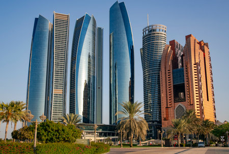 UAE, ABU DHABI, NOVEMBER, 2021 - Skyscrapers surrounded by a green park of palm trees at sunset in Abu Dhabi, capital of the United Arab Emirates.のeditorial素材