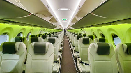 Latvia, Riga, December, 2021 - Empty Airbaltic aircraft cabin interior with green backlit and travel passenger seats .のeditorial素材