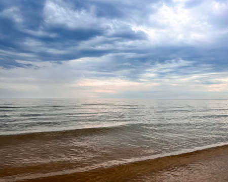 Calm waters of the Gulf of Riga before rain at sunset. Sunset, quiet summer evening.の写真素材
