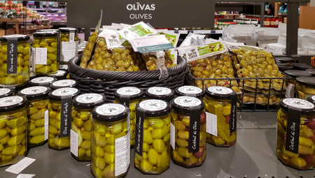 LATVIA, RIGA, JULY, 2022 - Canned green olives in a glass jars and vacuum packaging on shelves in Stockmann shopping mall, Riga. Latviaのeditorial素材